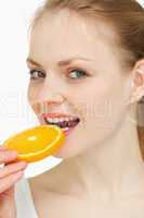 Close up of a woman placing an orange slice in her mouth