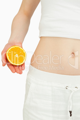 Close up of a woman placing an orange near her belly