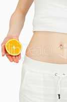 Close up of a woman placing an orange near her belly