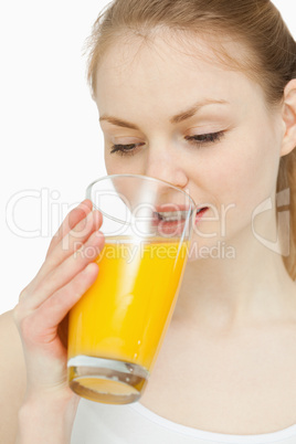 Woman drinking a glass of orange juice while looking at it