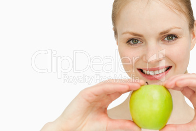 Joyful blond-haired woman presenting an apple