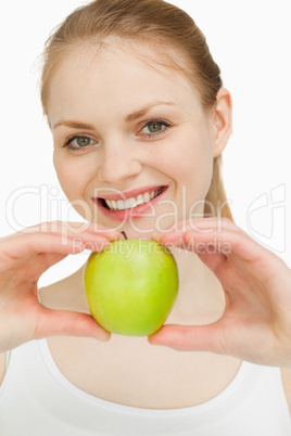 Blonde-haired girl smiling while presenting an apple