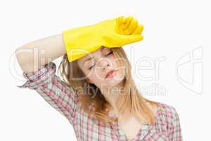 Woman wearing cleaning gloves while wiping her brow