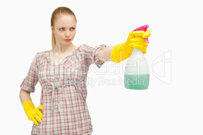 Serious woman holding a spray bottle while looking away