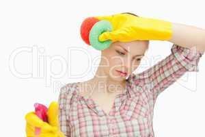 Young woman wiping her forehead while holding sponges