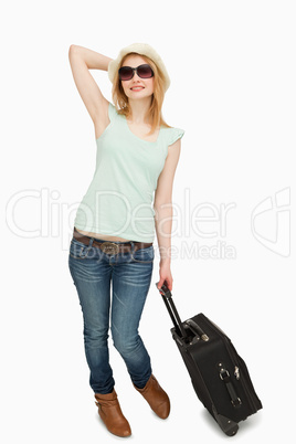 Young woman holding a suitcase while standing