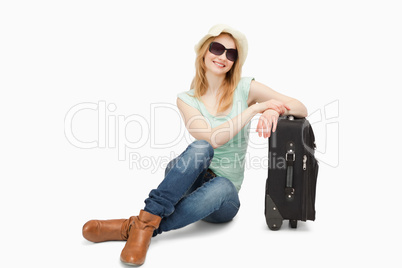 Woman sitting next to a suitcase