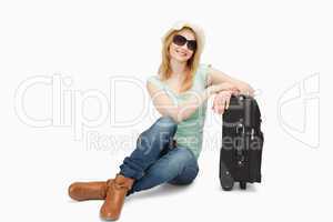 Woman sitting next to a suitcase