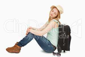 Tired woman sitting against a suitcase