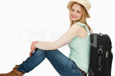 Smiling woman sitting near a suitcase