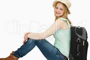 Smiling woman sitting near a suitcase
