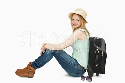 Cheerful woman sitting near a suitcase