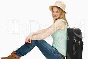 Joyful woman sitting near a suitcase