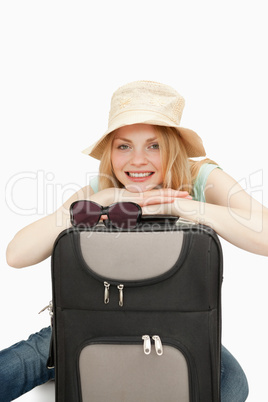 Woman leaning on a suitcase while sitting