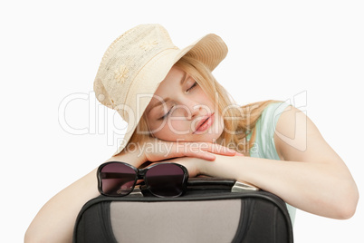 Woman asleep while leaning on a suitcase