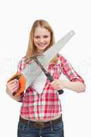 Smiling woman holding a saw and a hammer