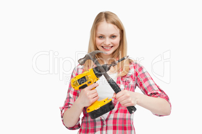Woman holding an electric screwdriver and a hammer