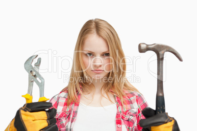 Serious woman holding a hammer and and a wrench