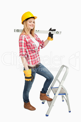 Woman holding a spirit level next to a step ladder