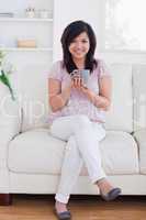 Woman holding a mug while sitting in a couch