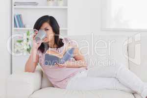Woman drinking from a mug while lying on a sofa