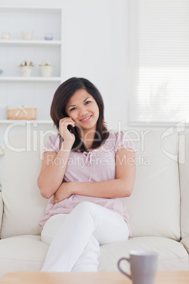 Smiling woman phoning while sitting on a couch Smiling woman phoning while sitting on a couch