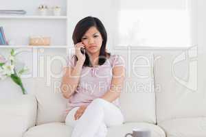 Woman phoning while she is sitting on a couch