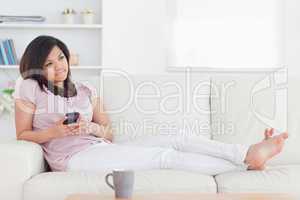 Barefoot woman lying on a couch while holding a telephone