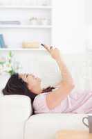 Woman laughing while resting on a couch and looking at a phone