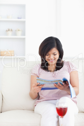 Woman sitting on a sofa while reading a magazine