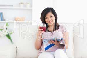Woman holding a magazine while holding a glass of red wine
