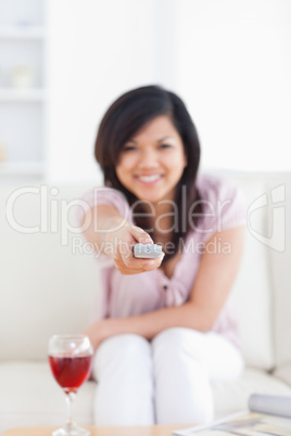 Blurred woman holding a television remote while sitting on a cou