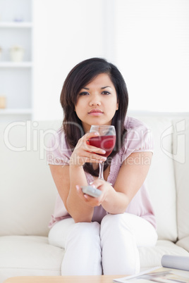 Woman sitting on a couch while holding a glass of red wine