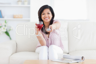 Woman sitting in a white couch while holding a glass of red wine