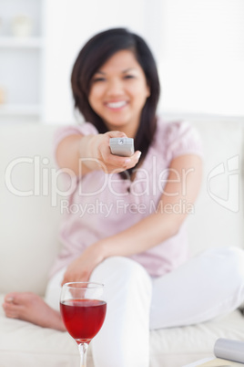 Woman sitting on a sofa while smiling and holding a remote