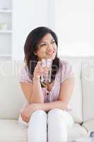 Woman sitting on a sofa and holding a glass of water
