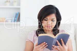 Woman sitting on a couch while reading a book