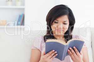 Woman sitting on a sofa while reading a book