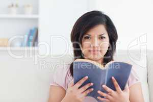 Woman sitting on a couch and holding a book