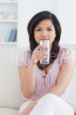 Woman sitting on a couch and holding a glass of water