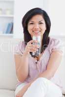Woman smiling while sitting on a couch and holding a glass of wa