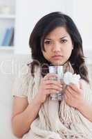 Sick woman holding a tissue and a glass of water