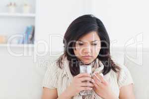 Woman holding a glass of water while being cold
