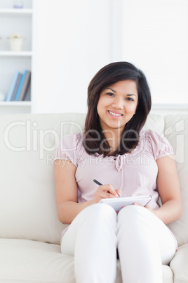 Woman sitting on a couch while sitting and writing on a notebook