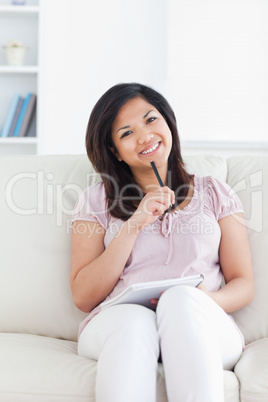 Woman smiling and holding a pen and a notebook