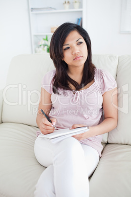 Thinking woman writing in a notebook