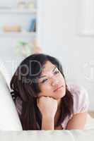 Thinking woman lying on a couch while holding her head with her