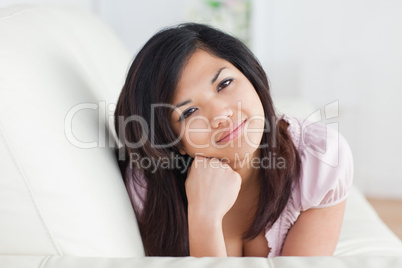 Woman resting on a sofa while holding her head with her fist