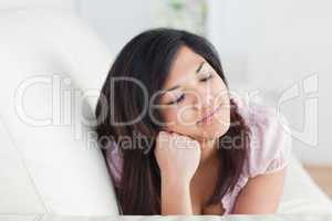 Woman closing her eyes while resting on a couch