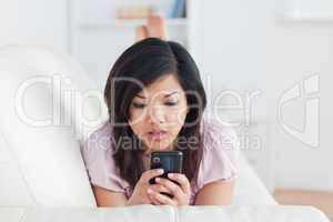 Surprised woman looking at a phone on a sofa